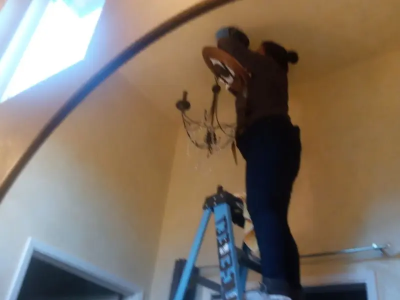Electrician installing a chandelier in a Bedford residence